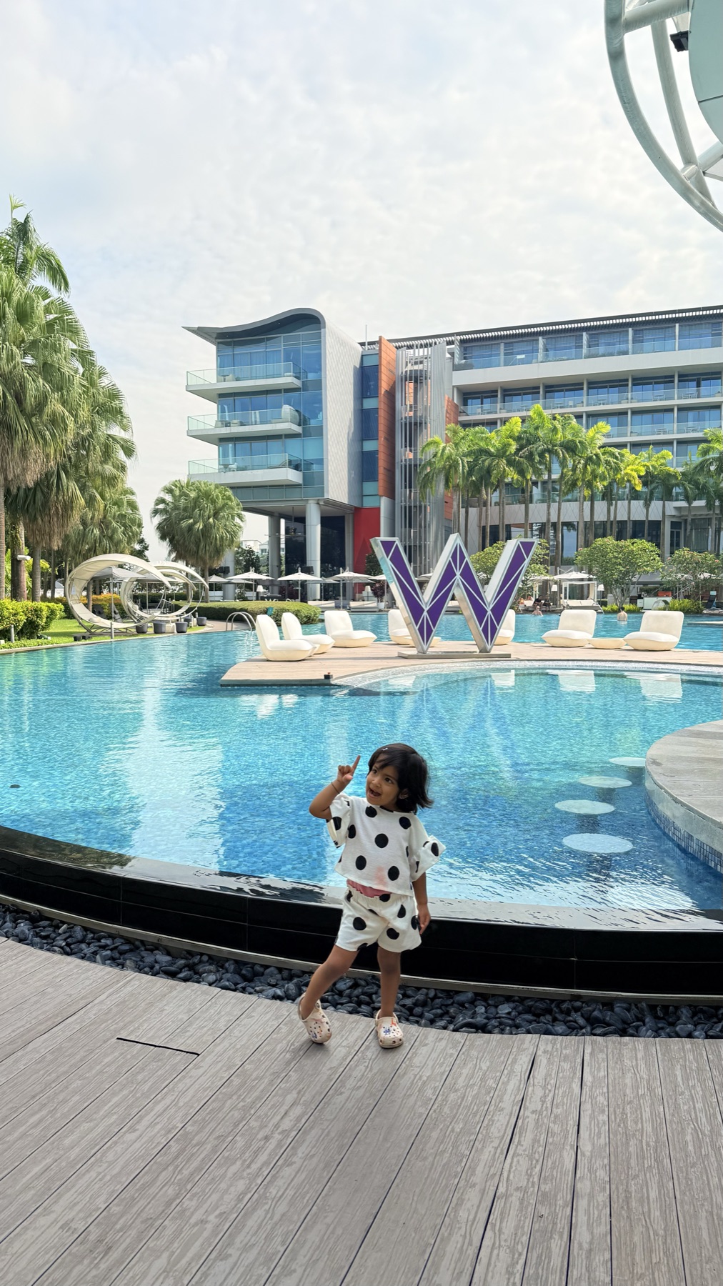 Our daughter beside the signature W sculpture at the W Singapore — Sentosa Cove pool